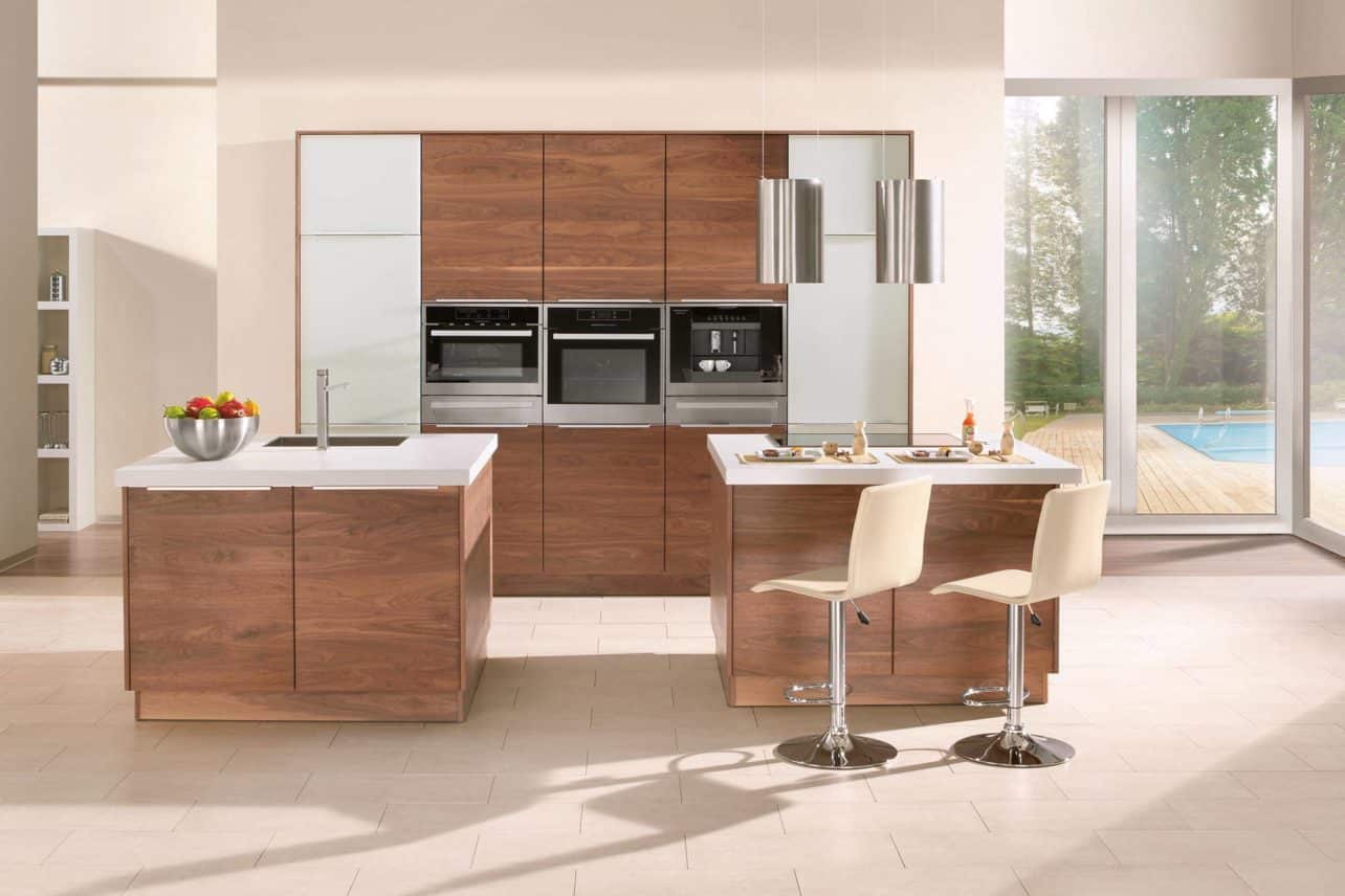Moderne Massivholzküche Noce in amerikanischem Nussbaum mit Fronten in weißem Glas, Gerätehochschrank, Spülinsel und Kochinsel mit zwei Sitzplätzen